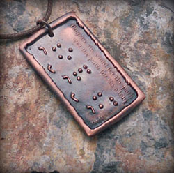Copper pendant with braille lettering.