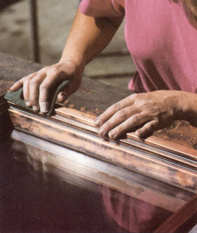 craft woman working on copper window frame