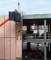 Crane lifting a copper and glass exterior wall for a building
