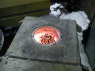 The photograph shows copper pellets being placed in the furnace crucible.